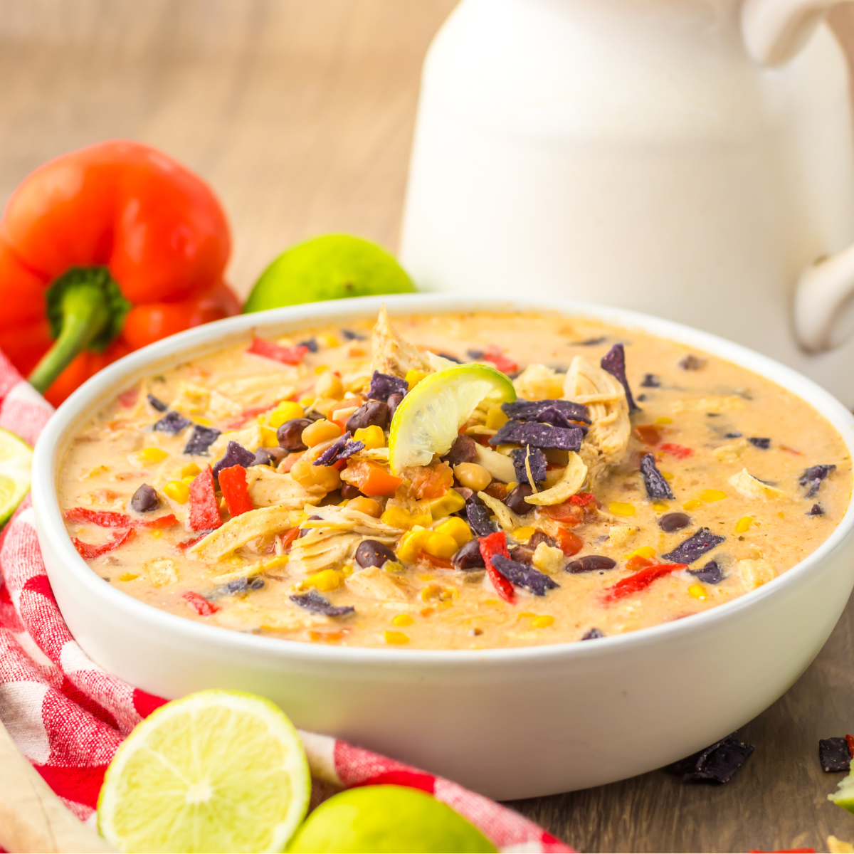 Side view of Slow Cooker Tortilla Soup in a white bowl with a white and red checkered napkin.