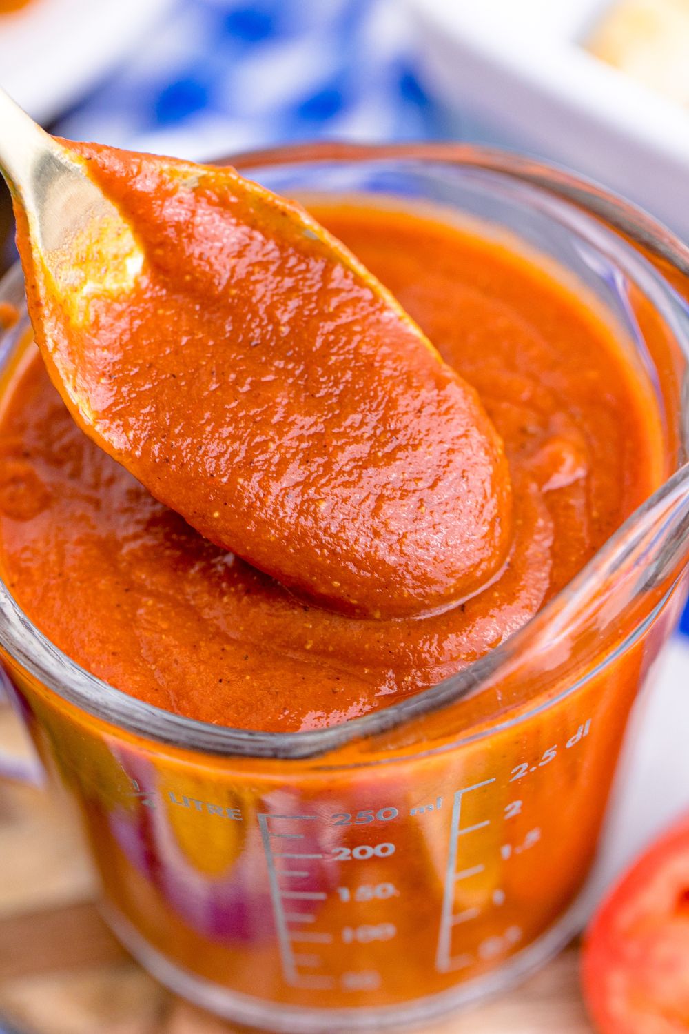 spoon with Homemade Enchilada Sauce on it above container with more sauce 