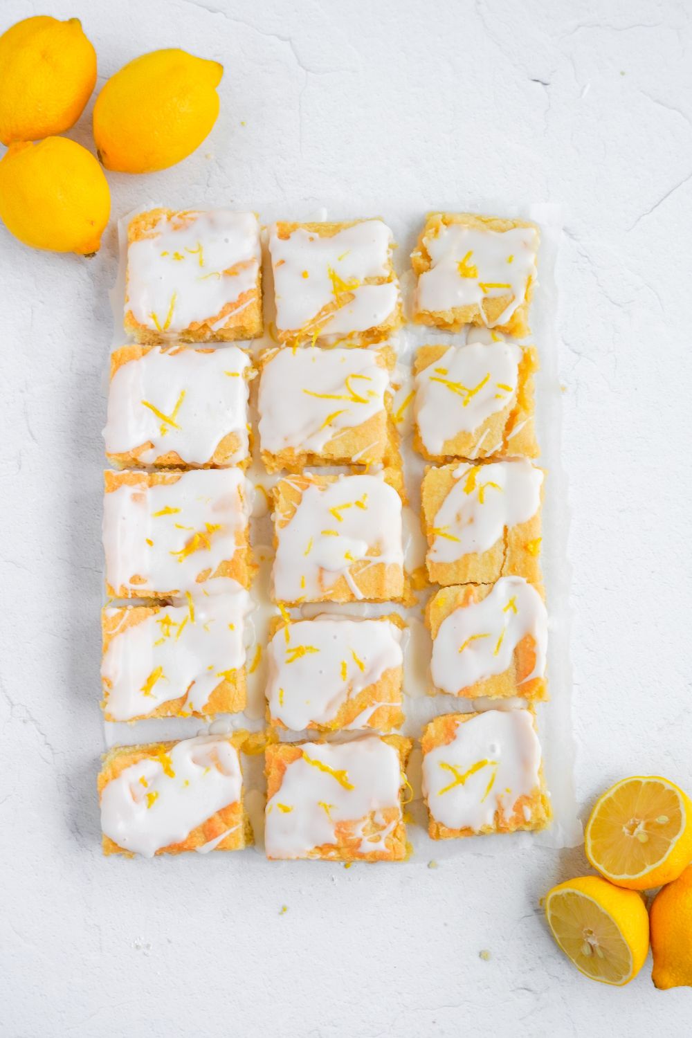 cut Lemon Sugar Cookie Bars on table with lemons on edge of bars 