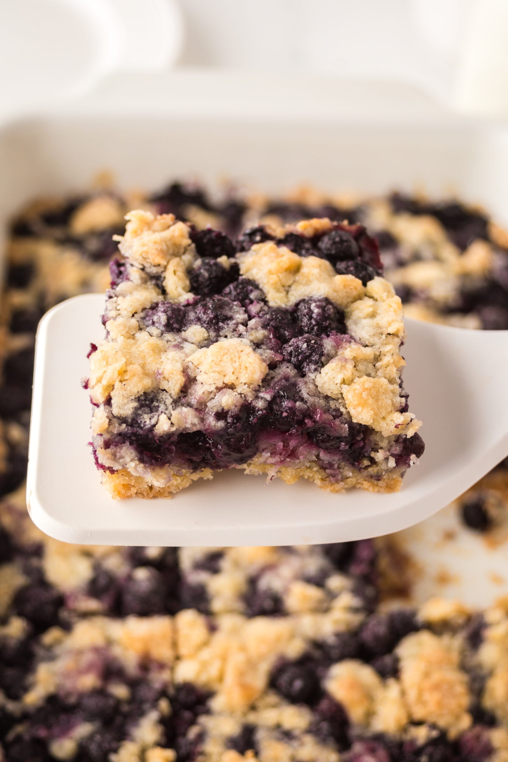 blueberry crumble bar being lifted up by a white spatula