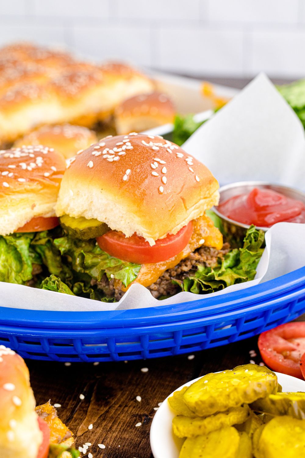 Classic Cheeseburger Sliders in baskets on table with some condiments around tray 