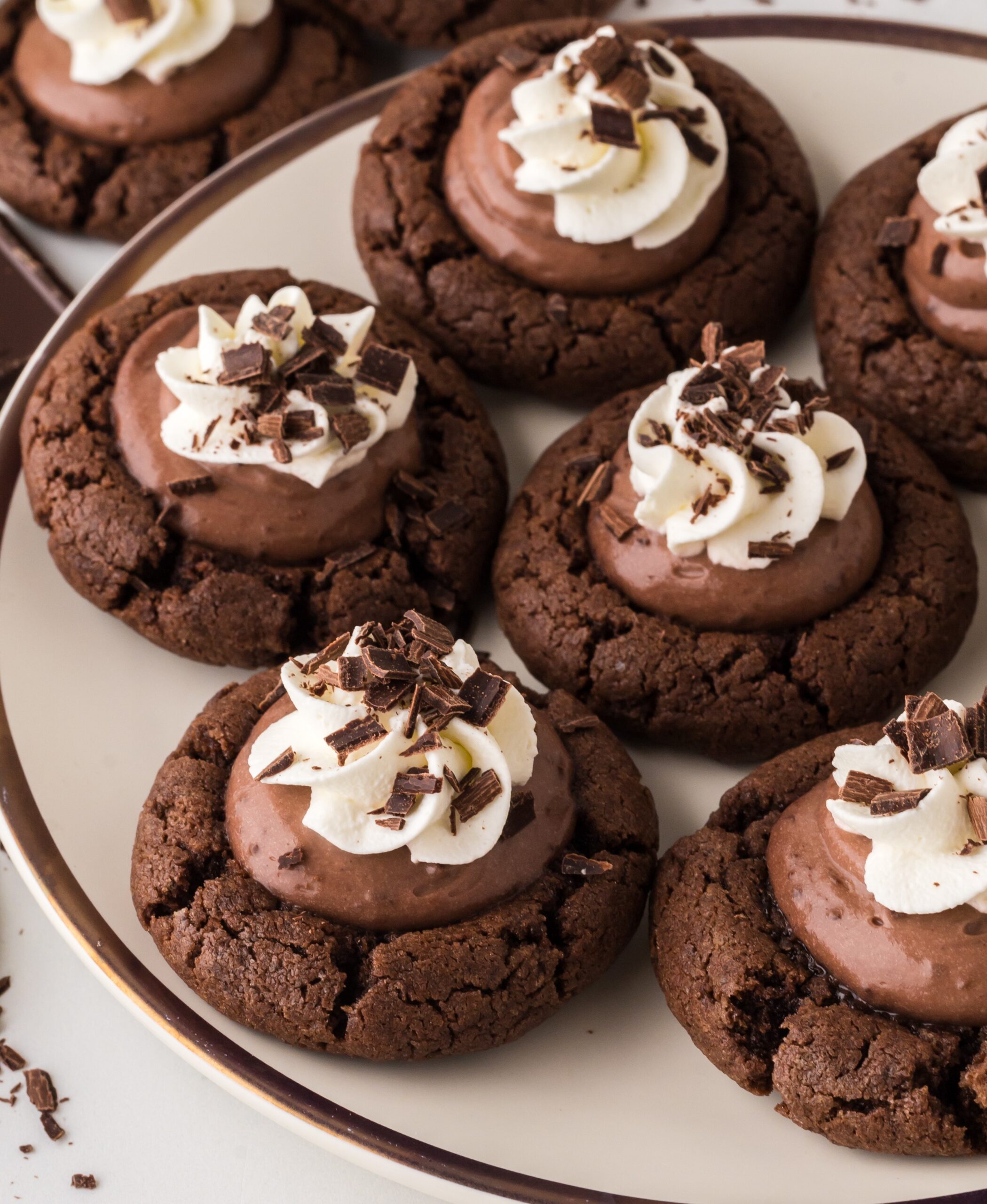 up close shot of the Chocolate Pie Cookies on a white plate topped with whipped cream and chocolate shavings 