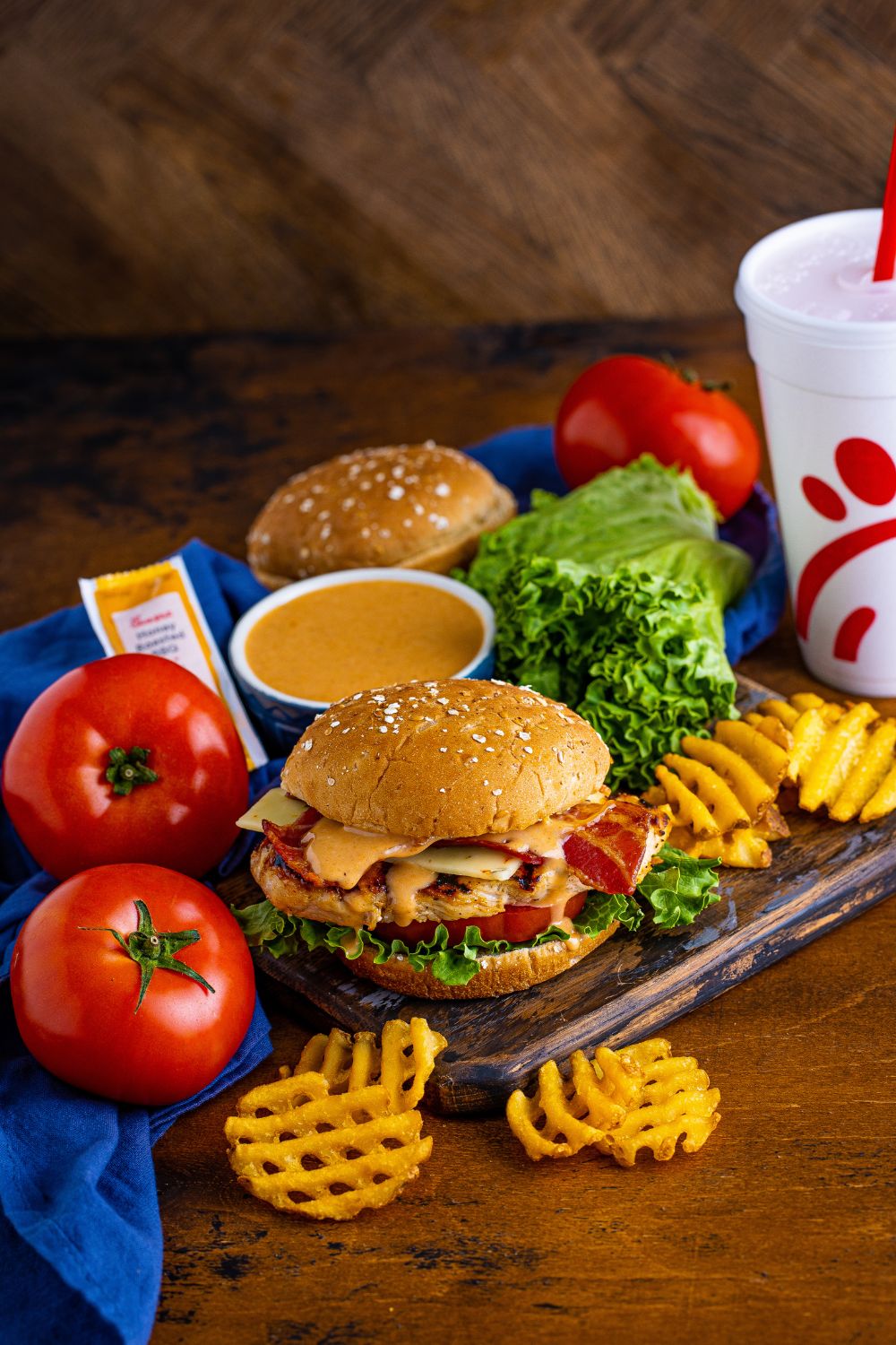 view of table with a Chick Fil A Grilled Chicken Sandwich, drink, fries, sauce and more on table 