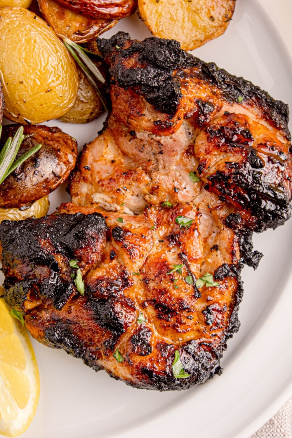 Grilled Chicken Thigh on plate with some roasted potatoes to the side of it 