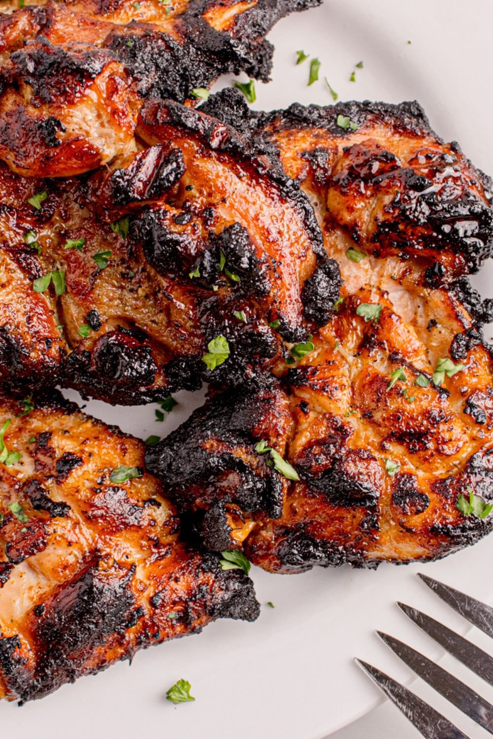 Grilled Chicken Thighs cooked and placed on plate with fork to the side 