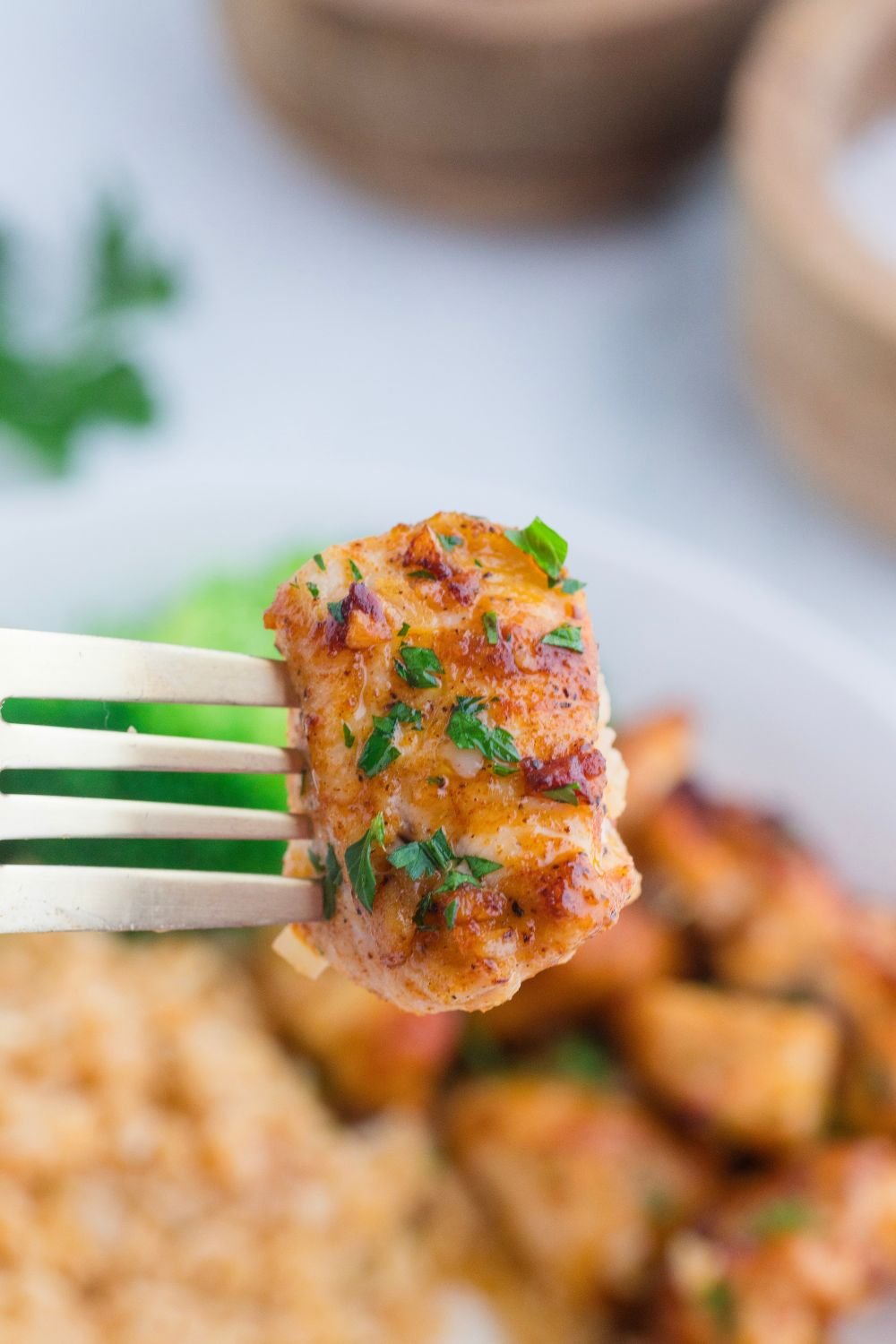 Garlic Butter Chicken Bite on fork above plate 