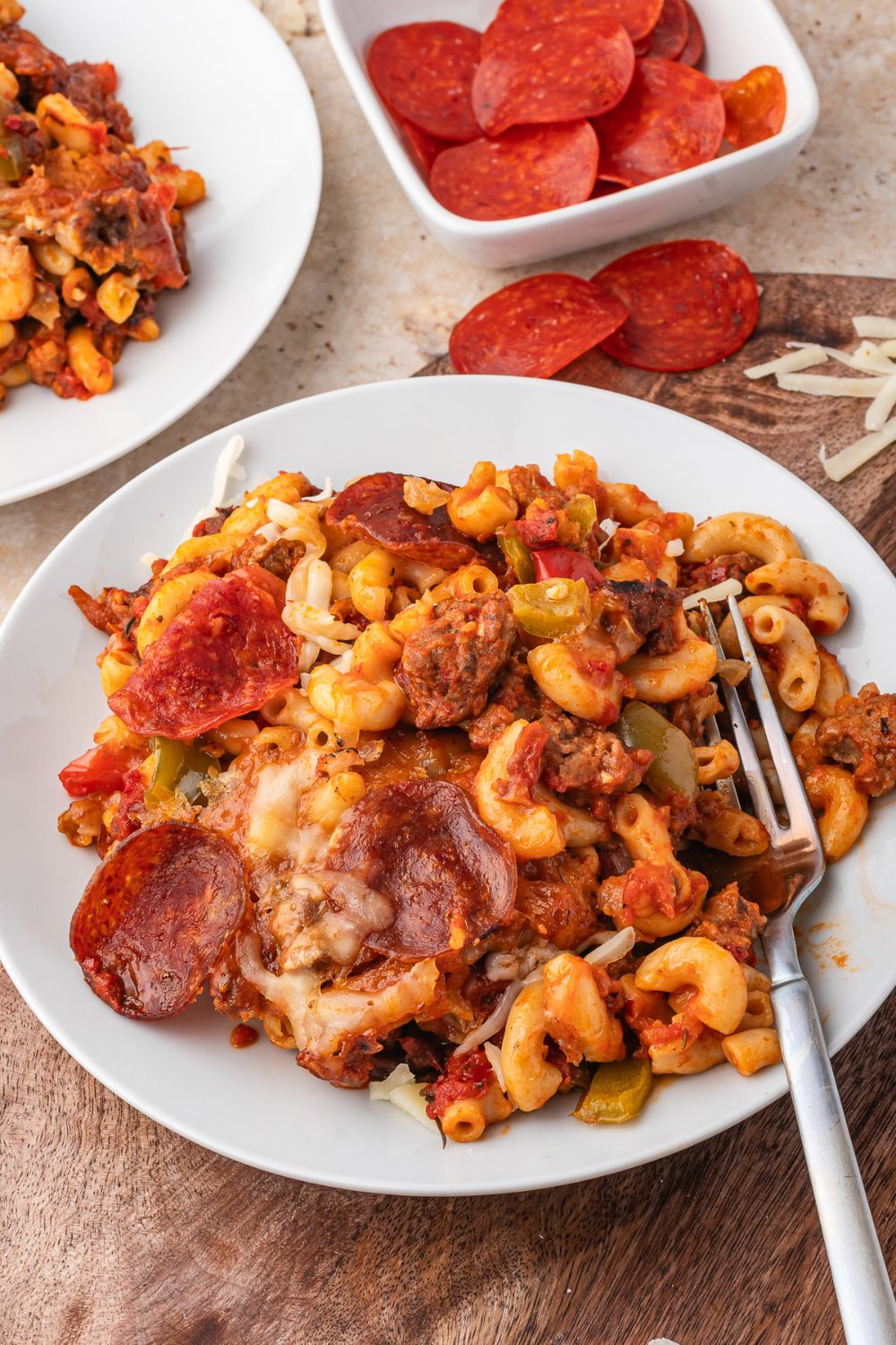 plates with cheesy pepperoni pizza pasta on each plate with forks 