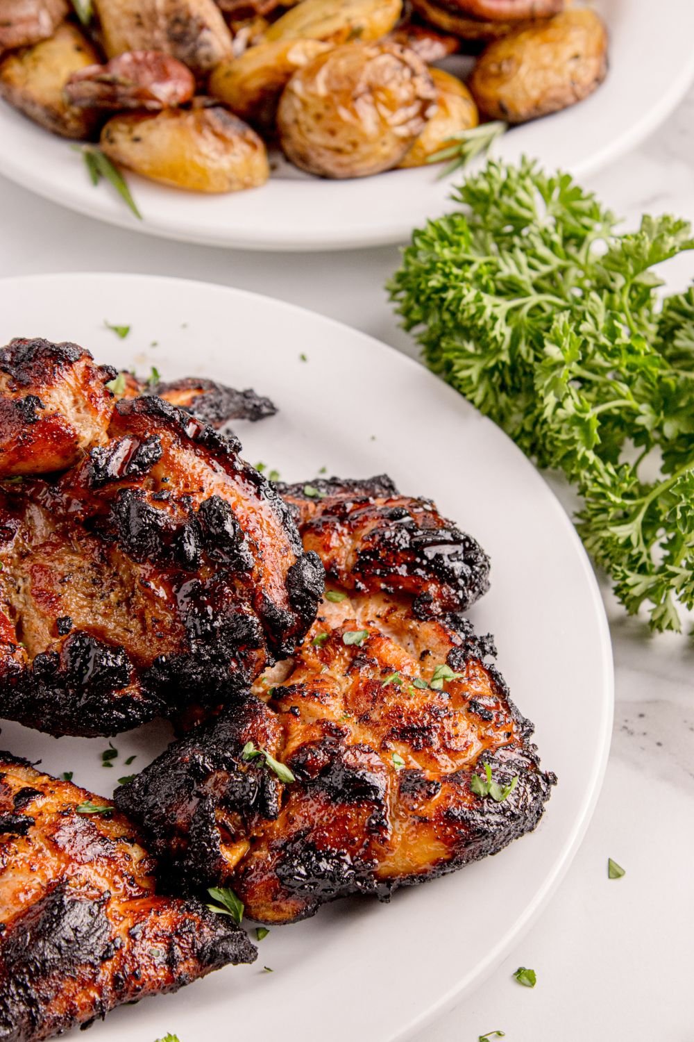 Grilled Chicken Thighs  on plate with parsley on side of plate 
