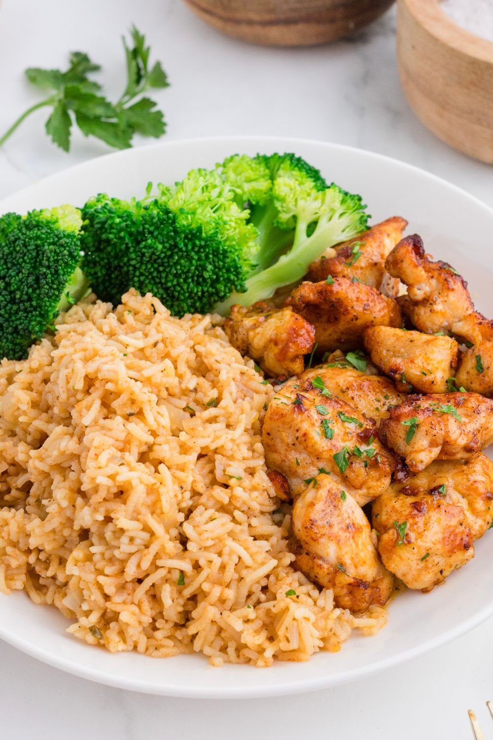Garlic Butter Chicken Bites on plate with a pile of rice and broccoli on side of plate 