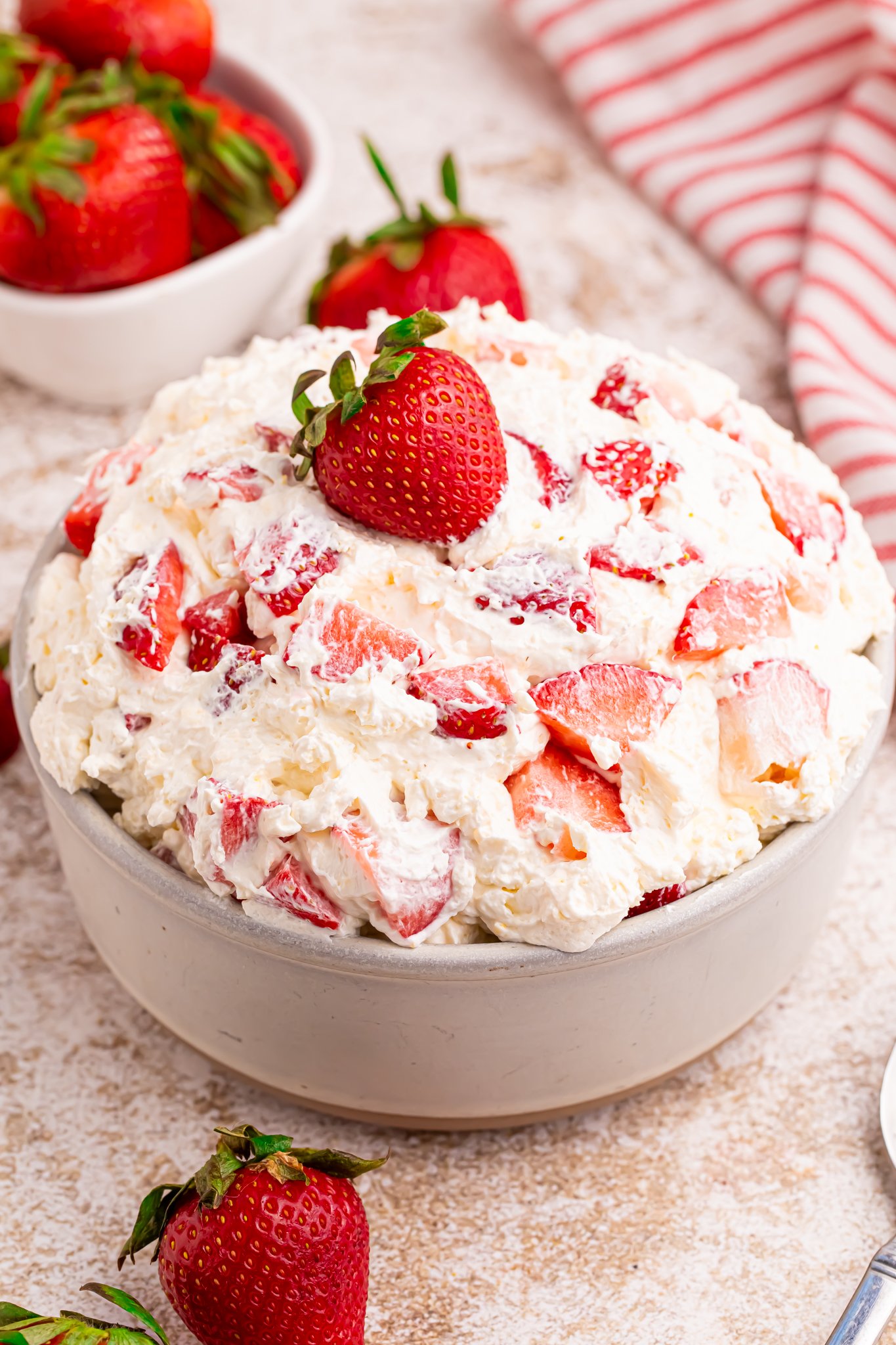 Overhead view of the strawberry cheesecake salad in a white bowl with a fresh strawberry on top. 