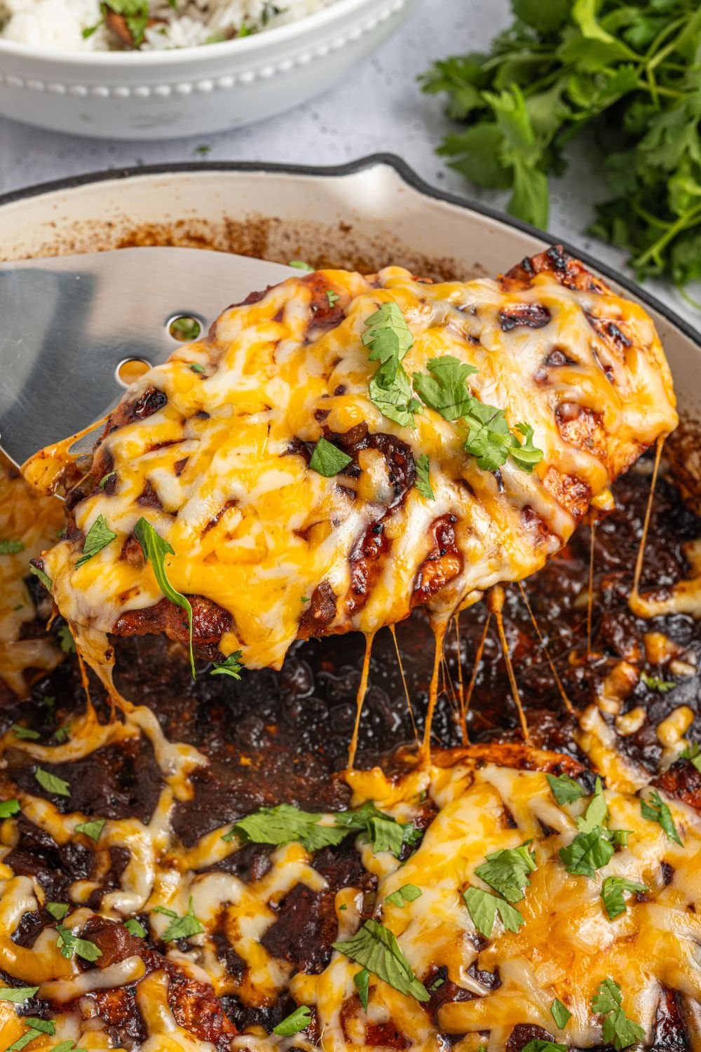 Cheesy Salsa Chicken being lifted out of pan that is garnished with parsley 