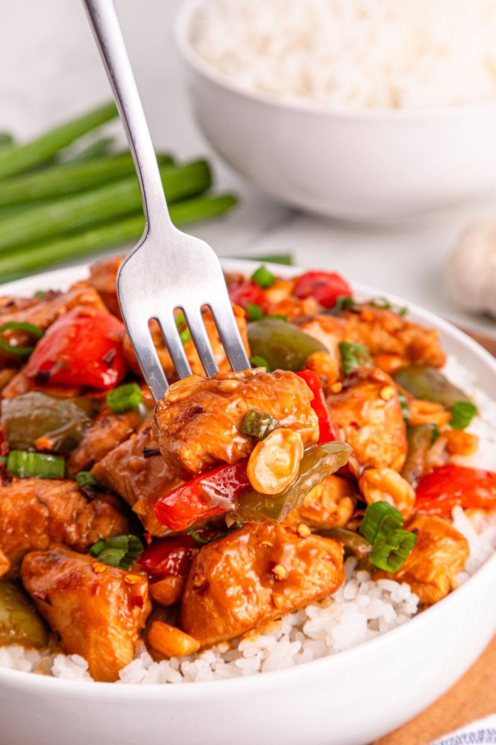 Better Than Takeout Kung Pao Chicken on a plate with rice and a fork poking into the chicken 