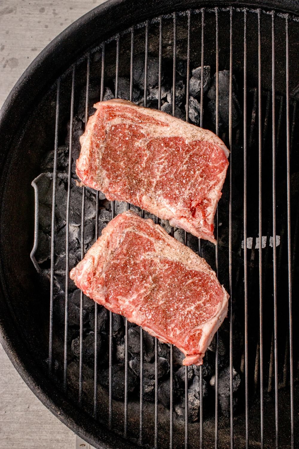 raw Ribeye Steaks on a charcoal grill