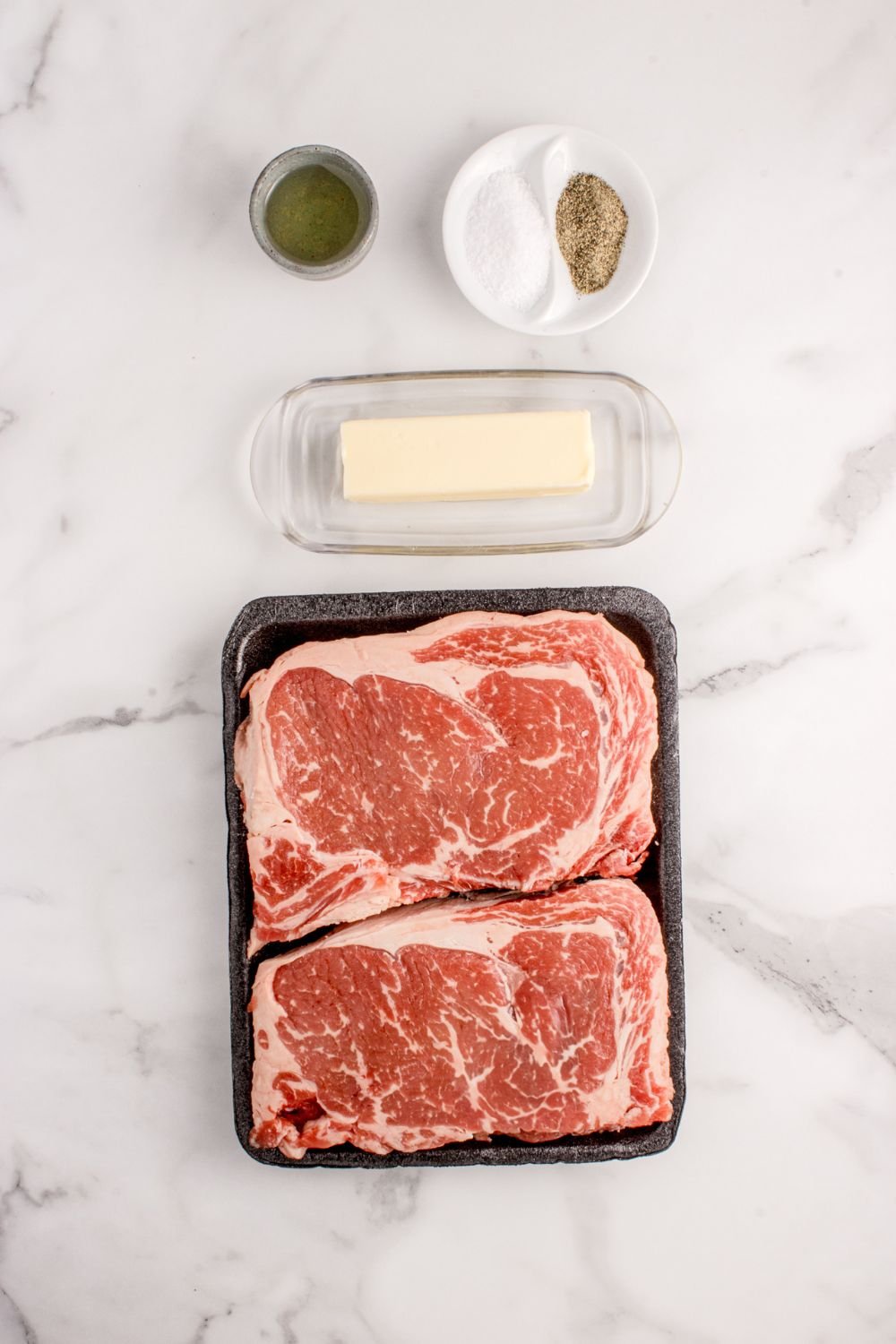 Grilled Ribeye Steaks ingredients on marble counter 