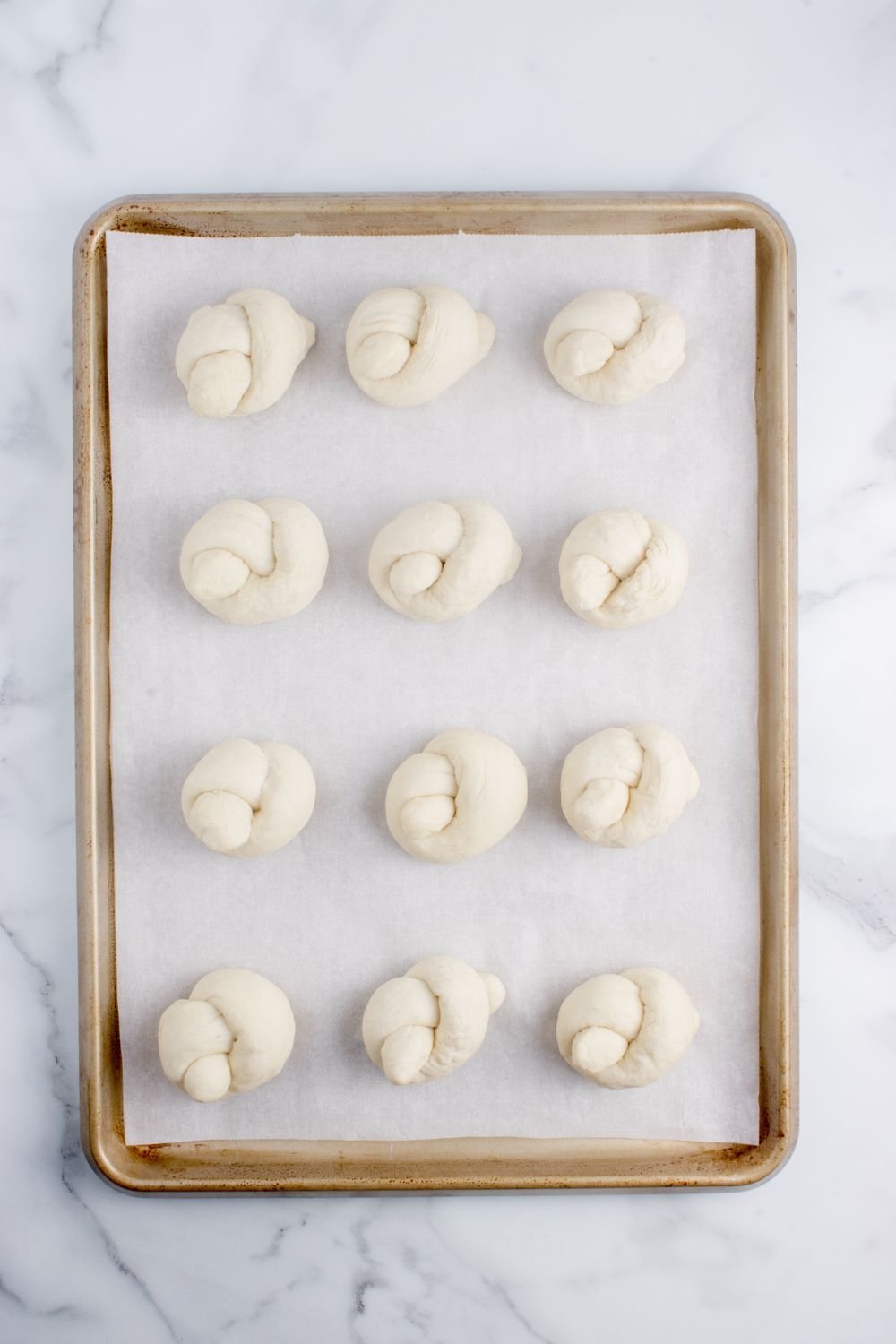 rolled garlic knots on a baking sheet on table 