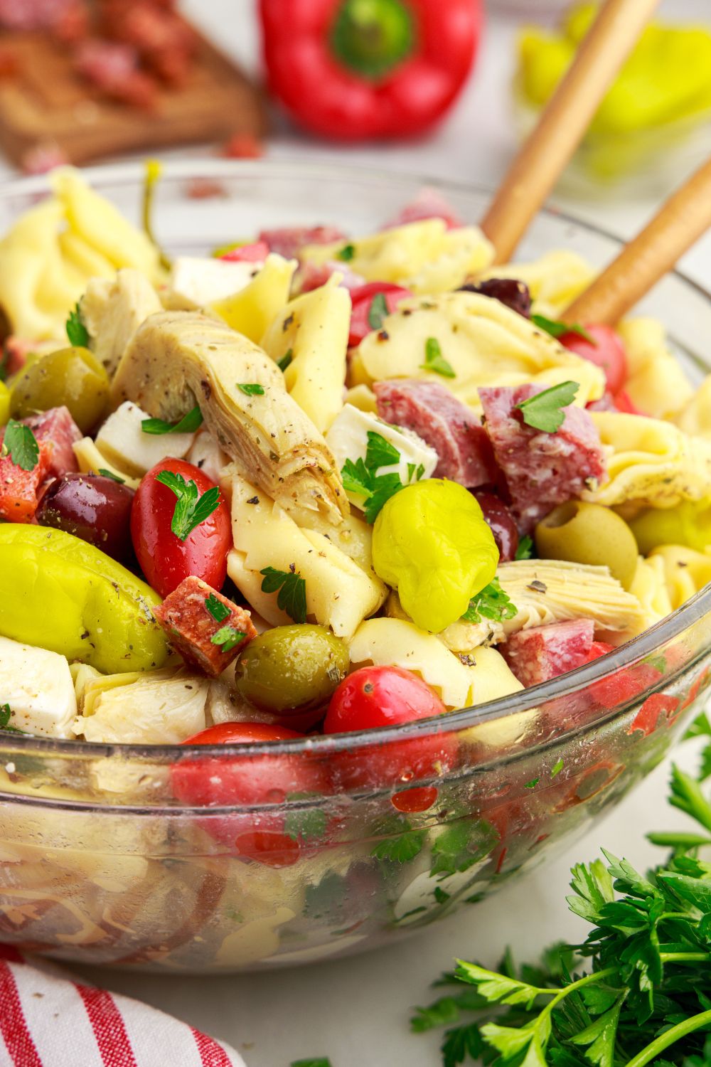 Antipasto Tortellini Pasta Salad in a glass bowl with spoons in the bowl 