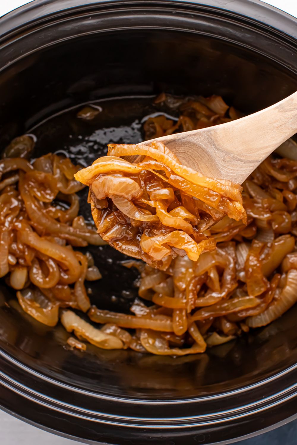 CrockPot Caramelized Onions being lifted out of CrockPot
