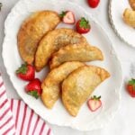 Deep Fried Strawberry Cheesecake Pies on table on a tray with fresh strawberries on plate