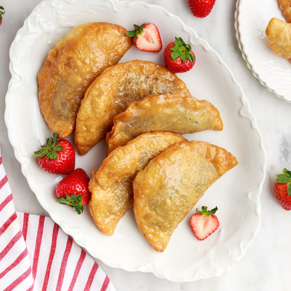 Deep Fried Strawberry Cheesecake Pies on table on a tray with fresh strawberries on plate 