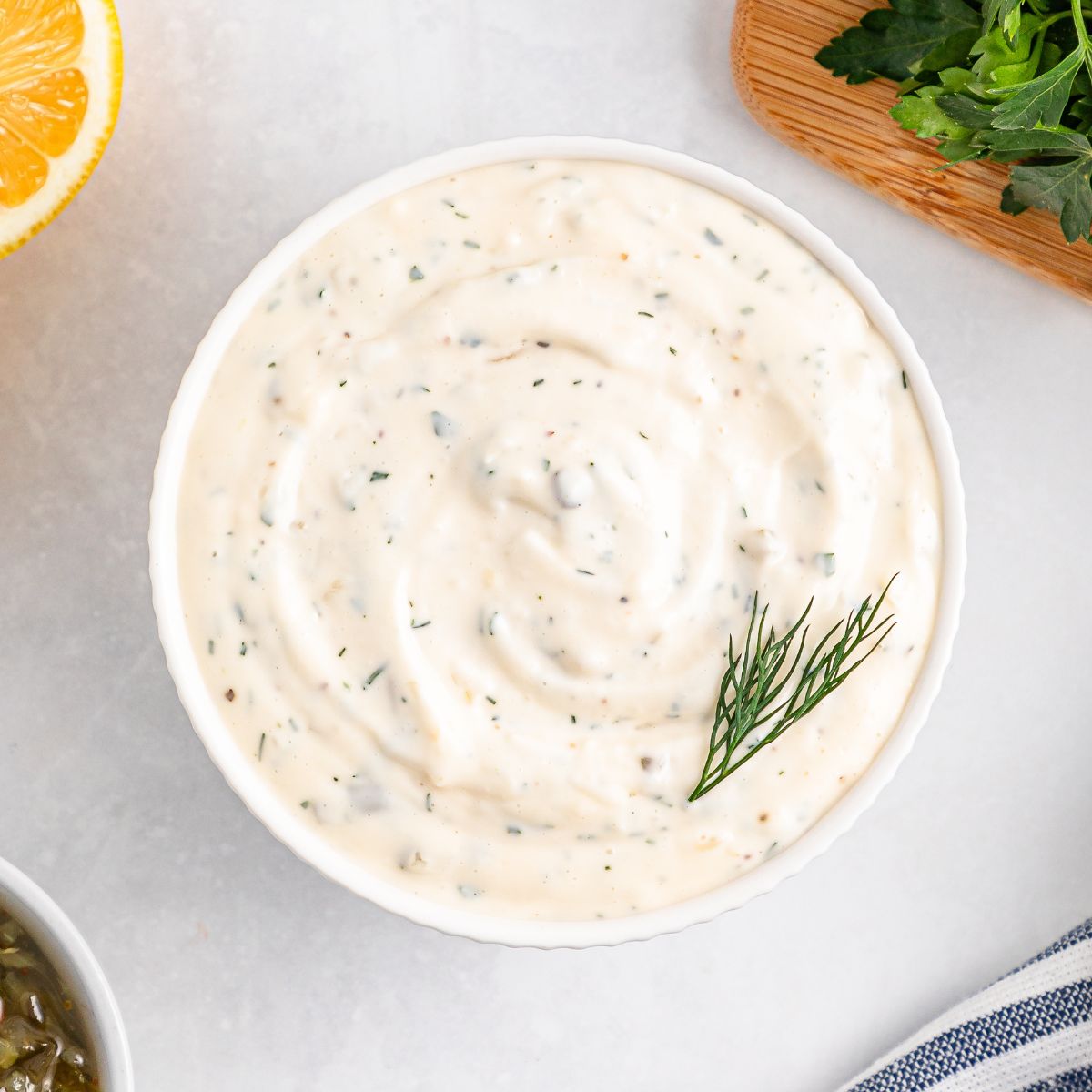 Easy Homemade Tarter Sauce in a white bowl on table with some dill garnish 