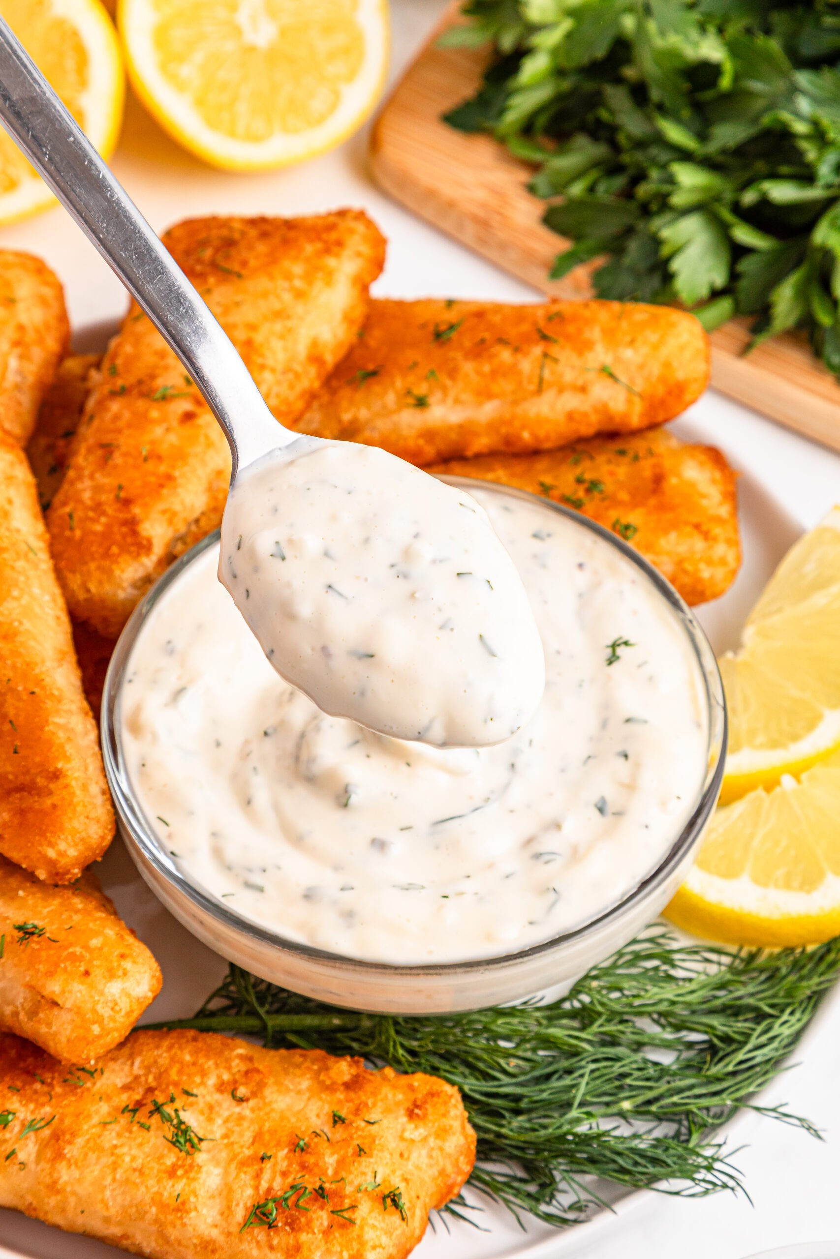 Easy Homemade Tarter Sauce in a small white bowl with a spoon lifting some up 