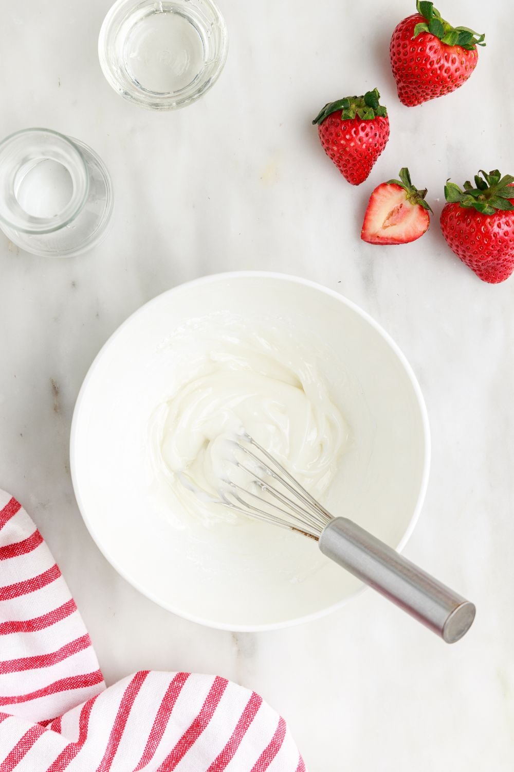 glaze in a white bowl on table for making Deep Fried Strawberry Cheesecake Pies