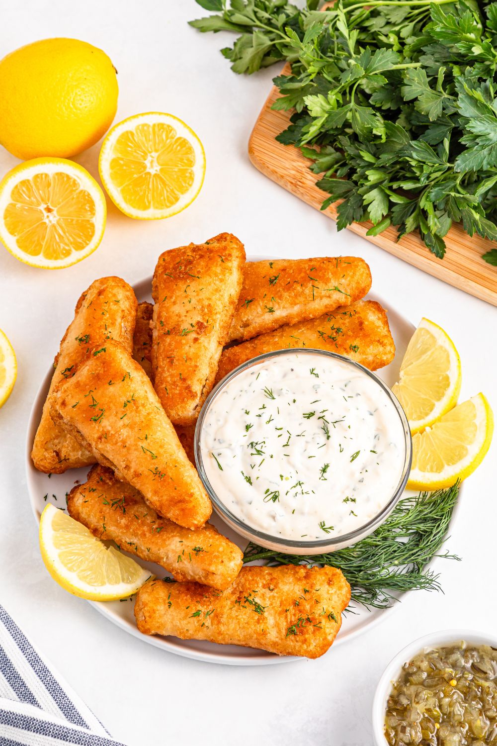 Easy Homemade Tarter Sauce in a bowl with lemon wedges to side and fish fillets 