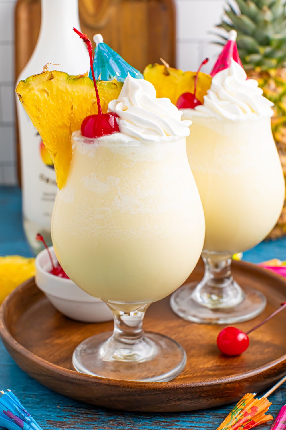 Frozen Malibu Piña Coladas in glasses on table with a bottle of malibu behind the drinks