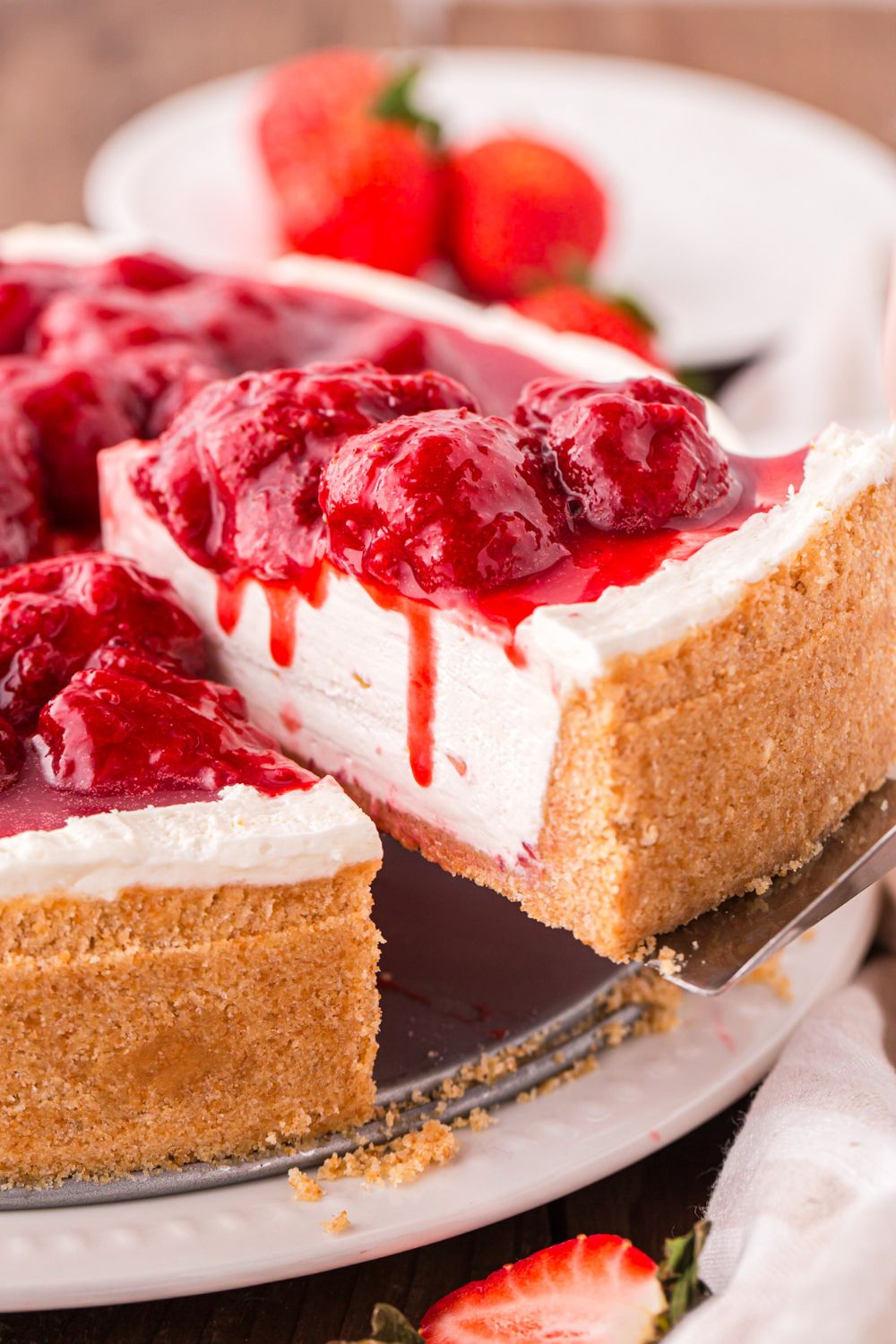 No Bake Strawberry Cheesecake on table with a slice being lifted out of the cheesecake 