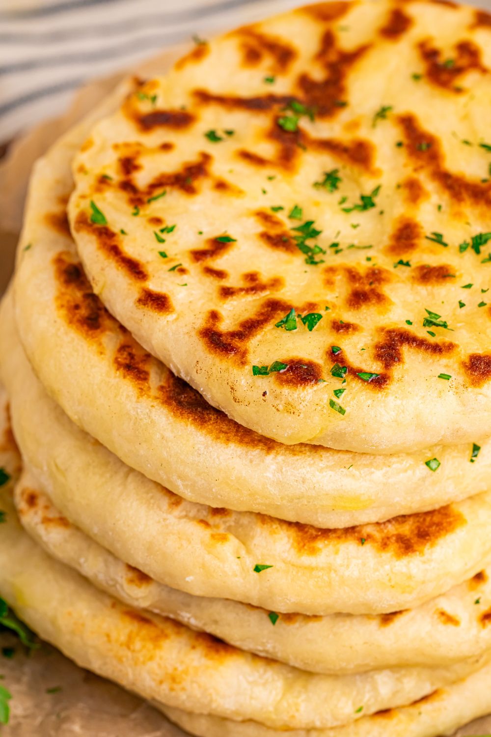 3 Ingredient Flatbread stacked on table with parsley and butter 