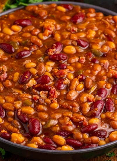 looking down to table with Crockpot Bourbon Brown Sugar Baked Beans in a serving bowl on a dark wood table