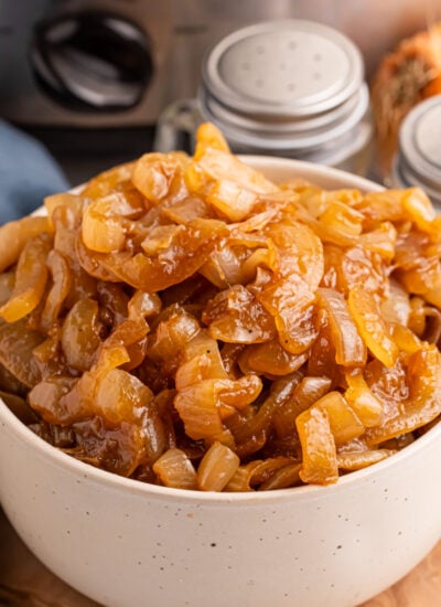 CrockPot Caramelized Onions in a bowl with the CrockPot behind it on table