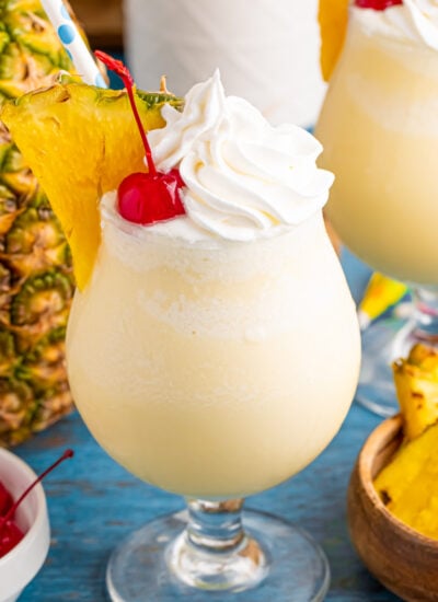 Frozen Malibu Piña Coladas in glasses with little umbrellas, pineapple slices and cherries