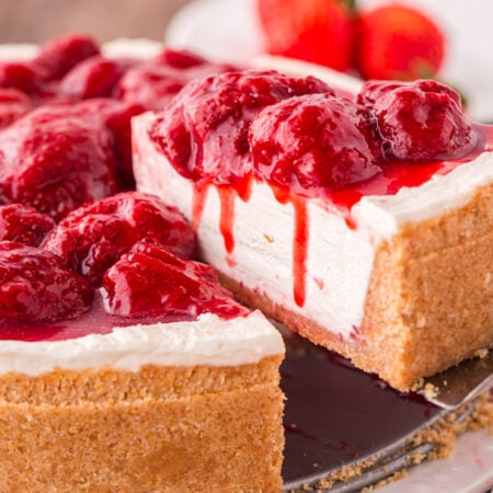 No Bake Strawberry Cheesecake on tray with a slice taken out to see how decadent the cheesecake is