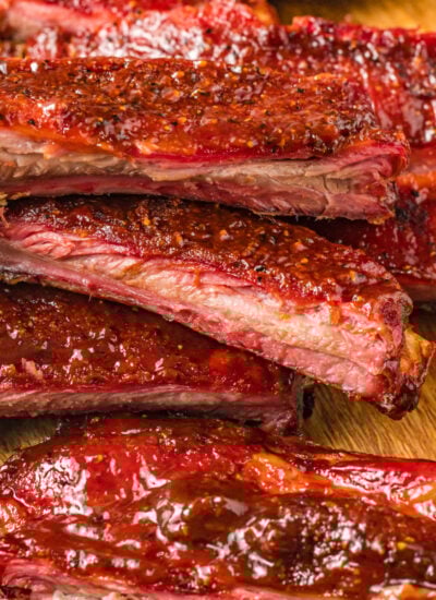 Grilled BBQ Baby Back Ribs placed on cutting board with part of them cut