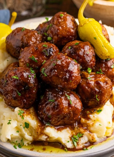 Crockpot Mississippi Meatballs on a plate with a bed of mashed potatoes underneath
