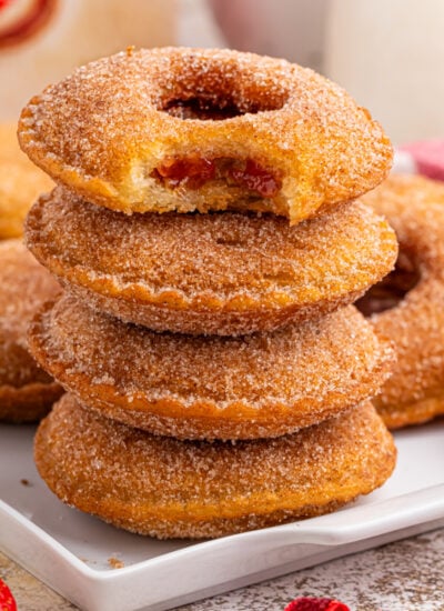 plate with Fried Strawberry Uncrustables that have been fried and rolled in sugar on plate with strawberries in front of plate