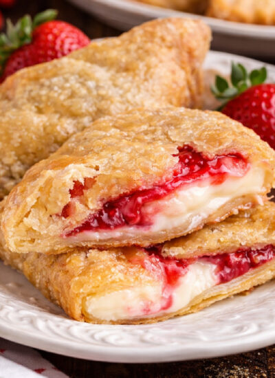 Deep Fried Strawberry Cheesecake Pies on a white dish with one cut open so you can see the inside