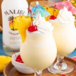 Frozen Malibu Piña Coladas in glasses with little umbrellas, pineapple slices and cherries