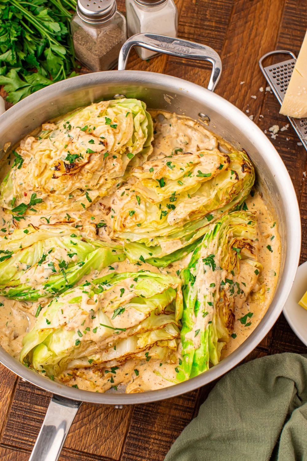 Garlic cabbage in skillet with a creamy sauce mixed in, and salt and pepper shaker to side of pan