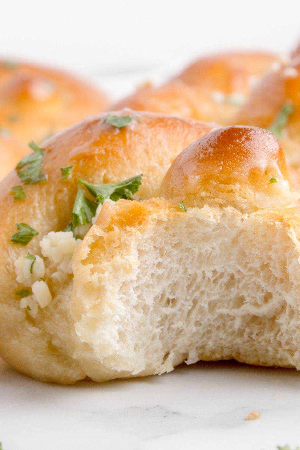 Homemade Garlic Knot sitting on table with a bite taken out of it 