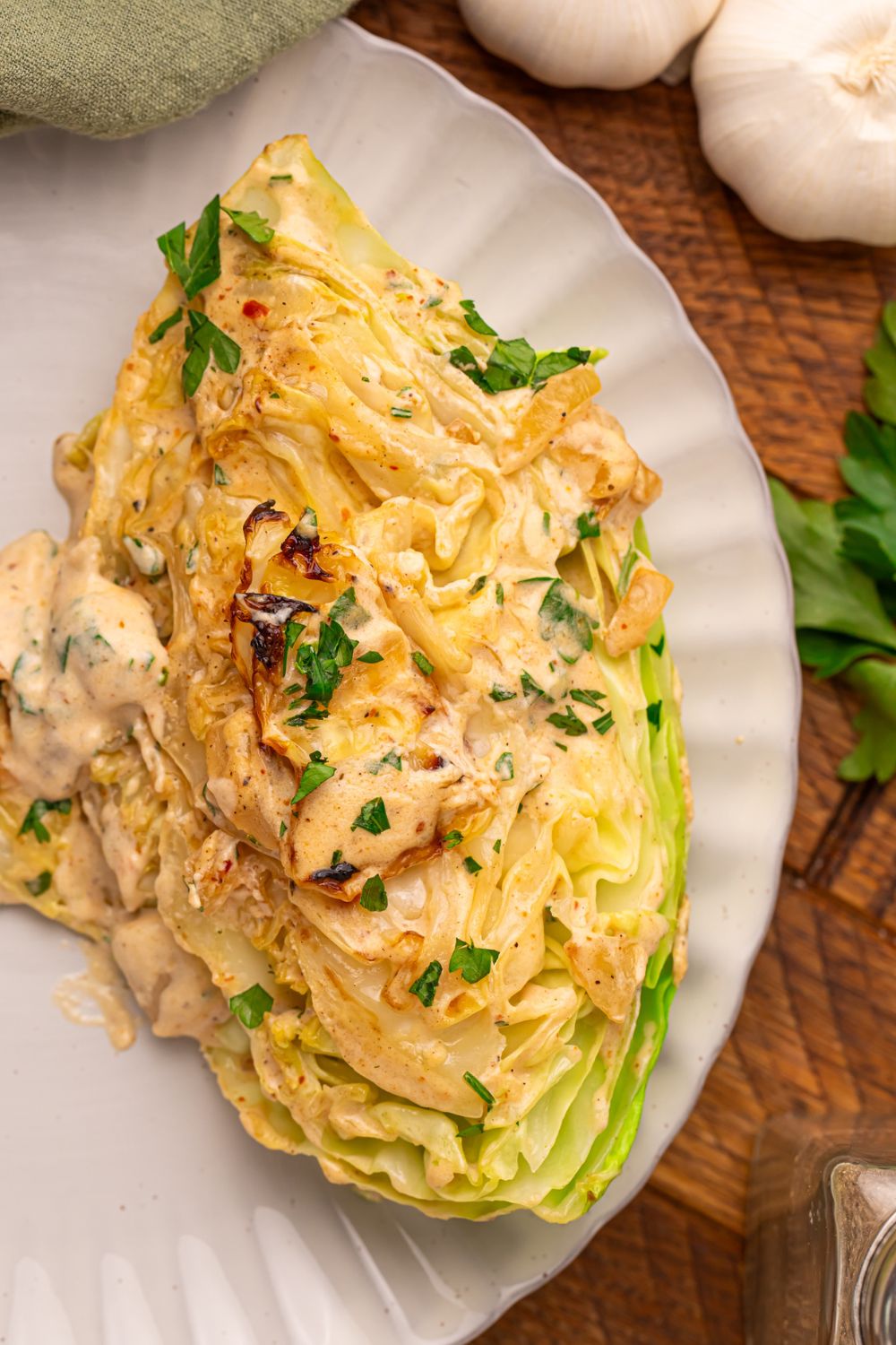 Creamy Garlic Parmesan Cabbage wedge on a plate topped with a creamy garlic sauce 