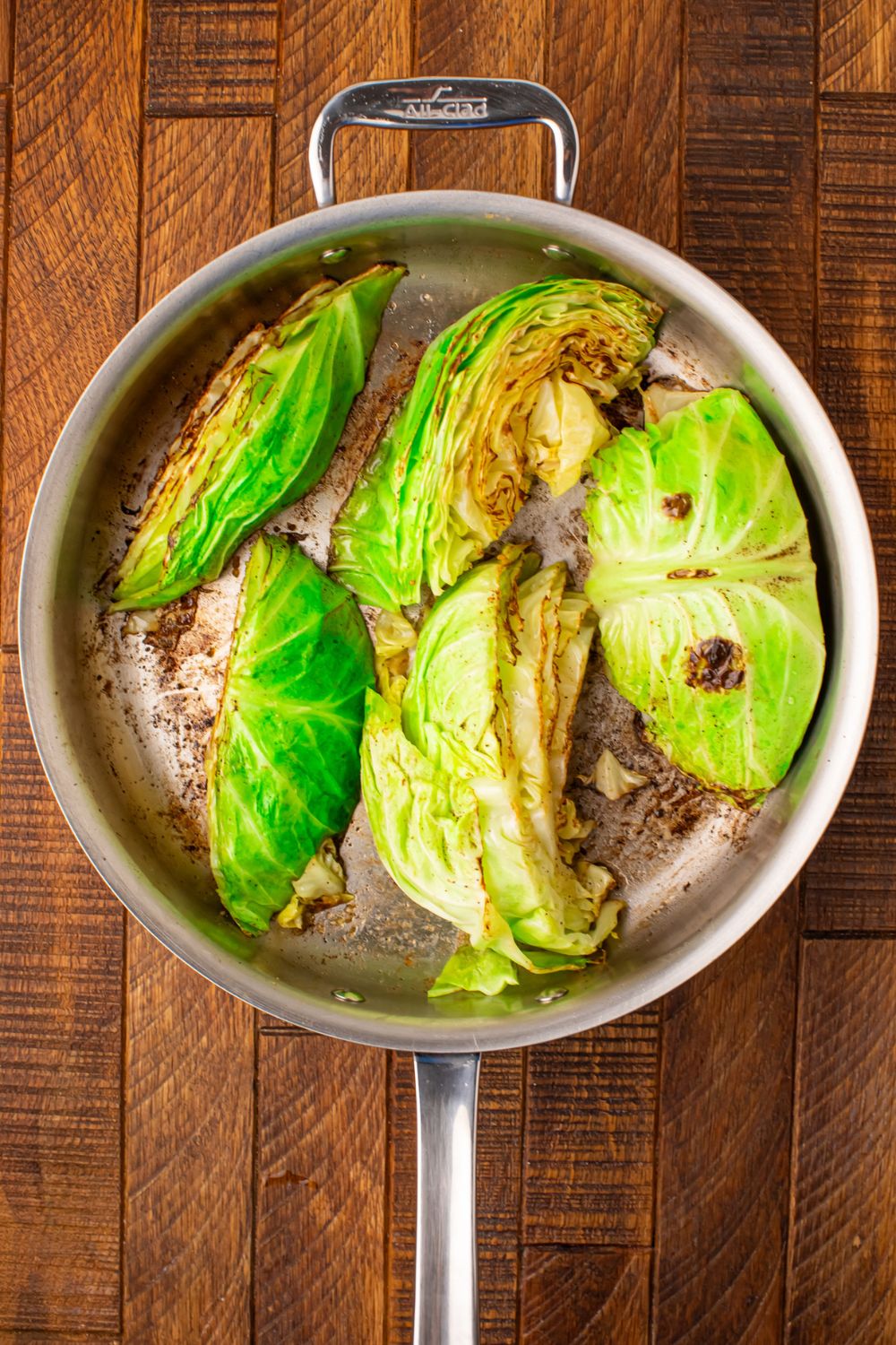 cabbage wedges being sauted in a skillet on table