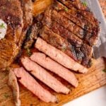 Grilled Ribeye Steak sliced on cutting board with a whole steak to side