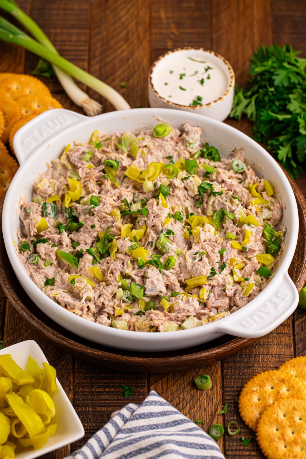 table set up with green onions, ranch dressing in a bowl, crackers, and a bowl of Pepperoncini Ranch Tuna Salad