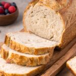Homemade Sourdough Bread on cutting board with a few slices cut out of the loaf of bread