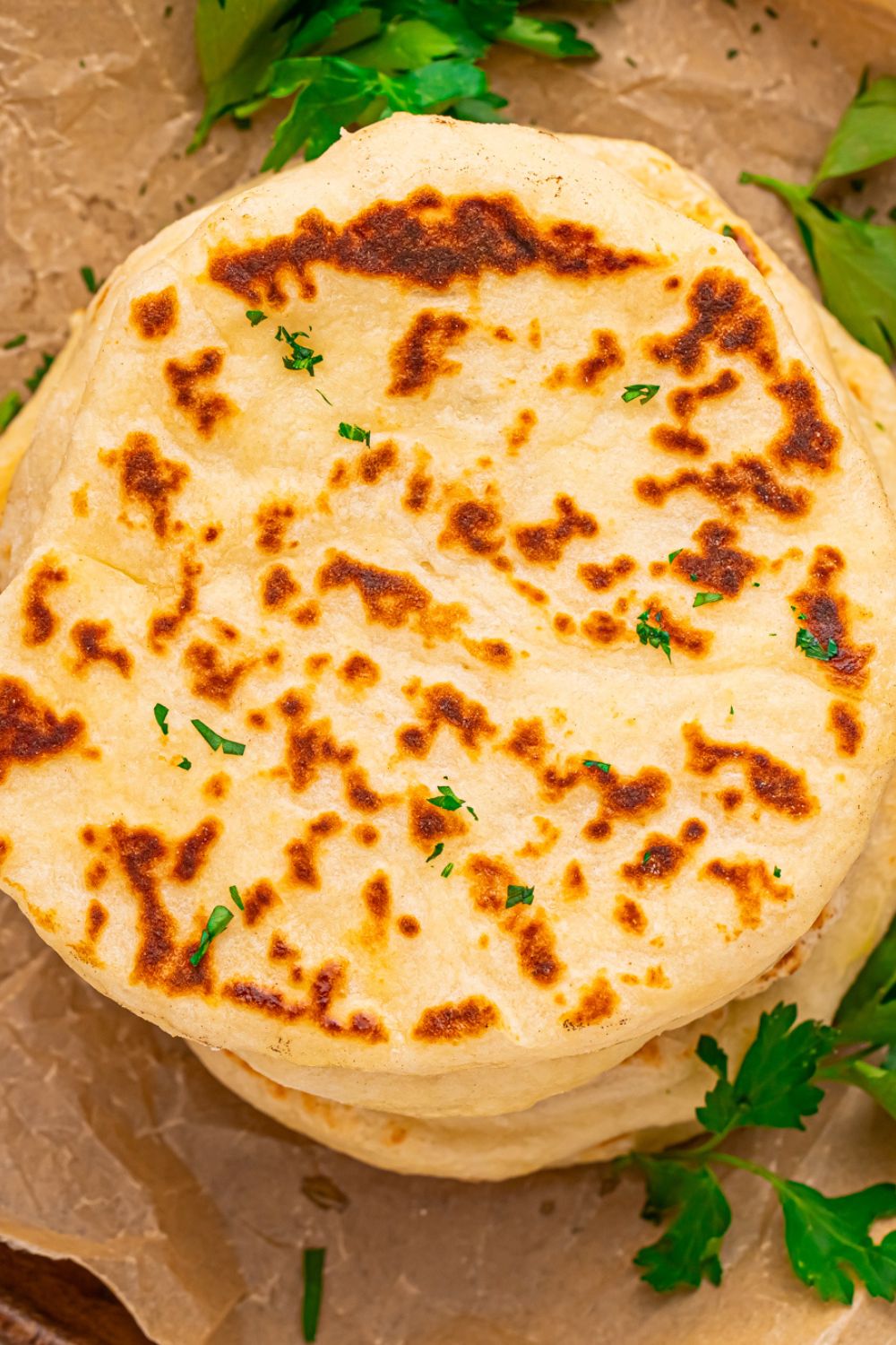 3 Ingredient Flatbreads stacked on top of one another on table with parsley around it 