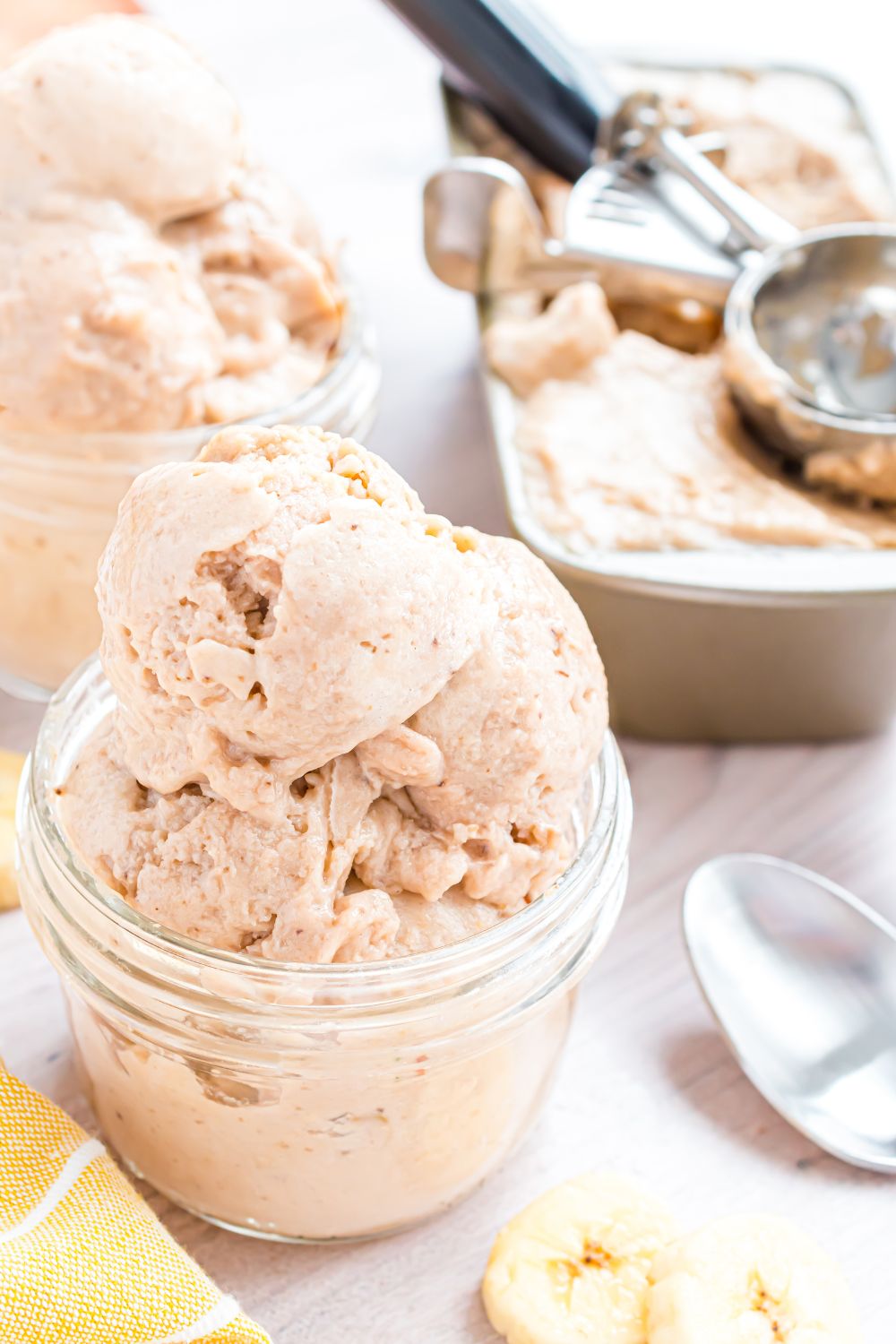 Banana Ice Cream piled in containers, and then a loaf pan with the rest of ice cream inside and ice cream scoop 