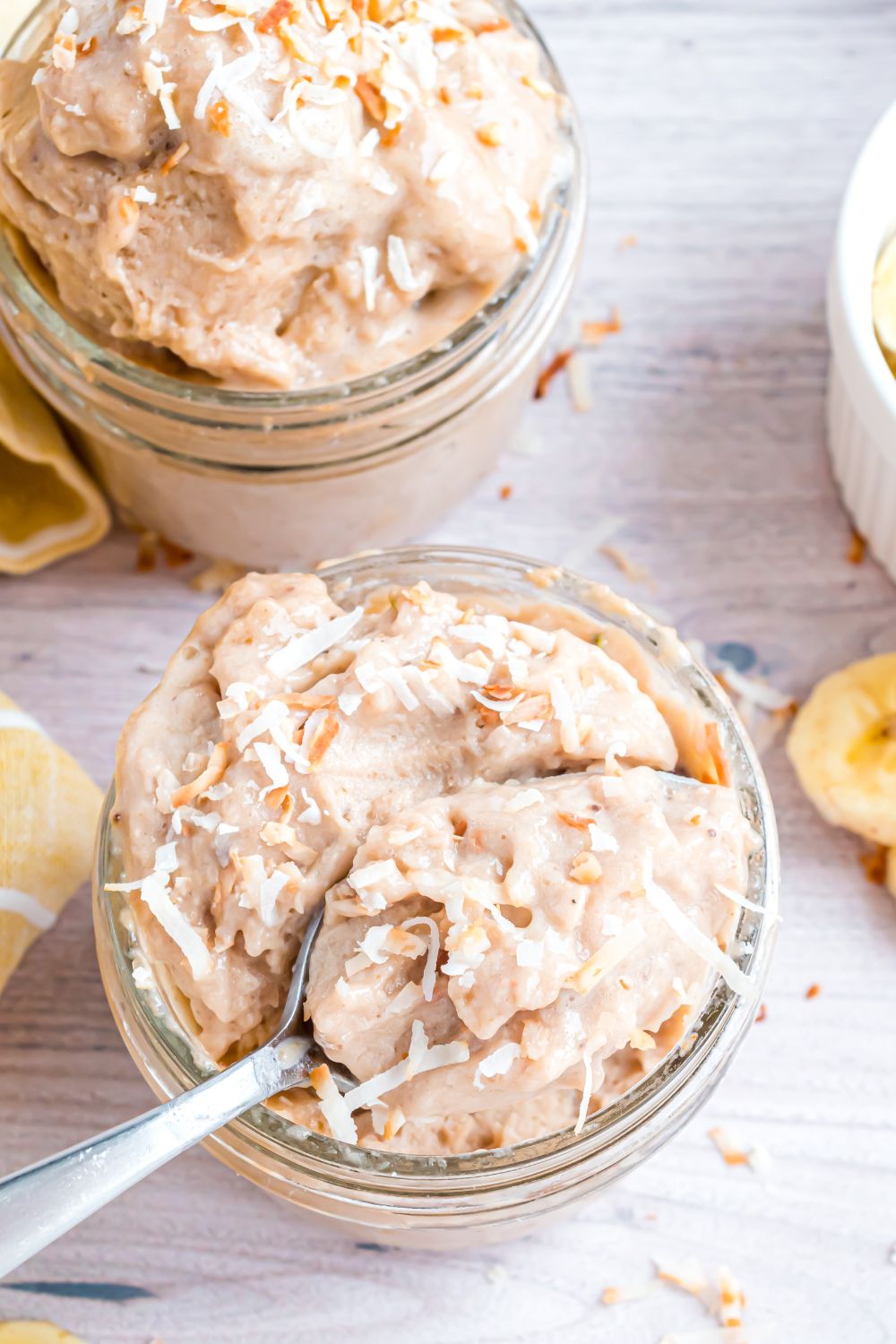 Banana Ice Cream in a glass bowl with spoon inside bowl and toppings on top of ice cream 