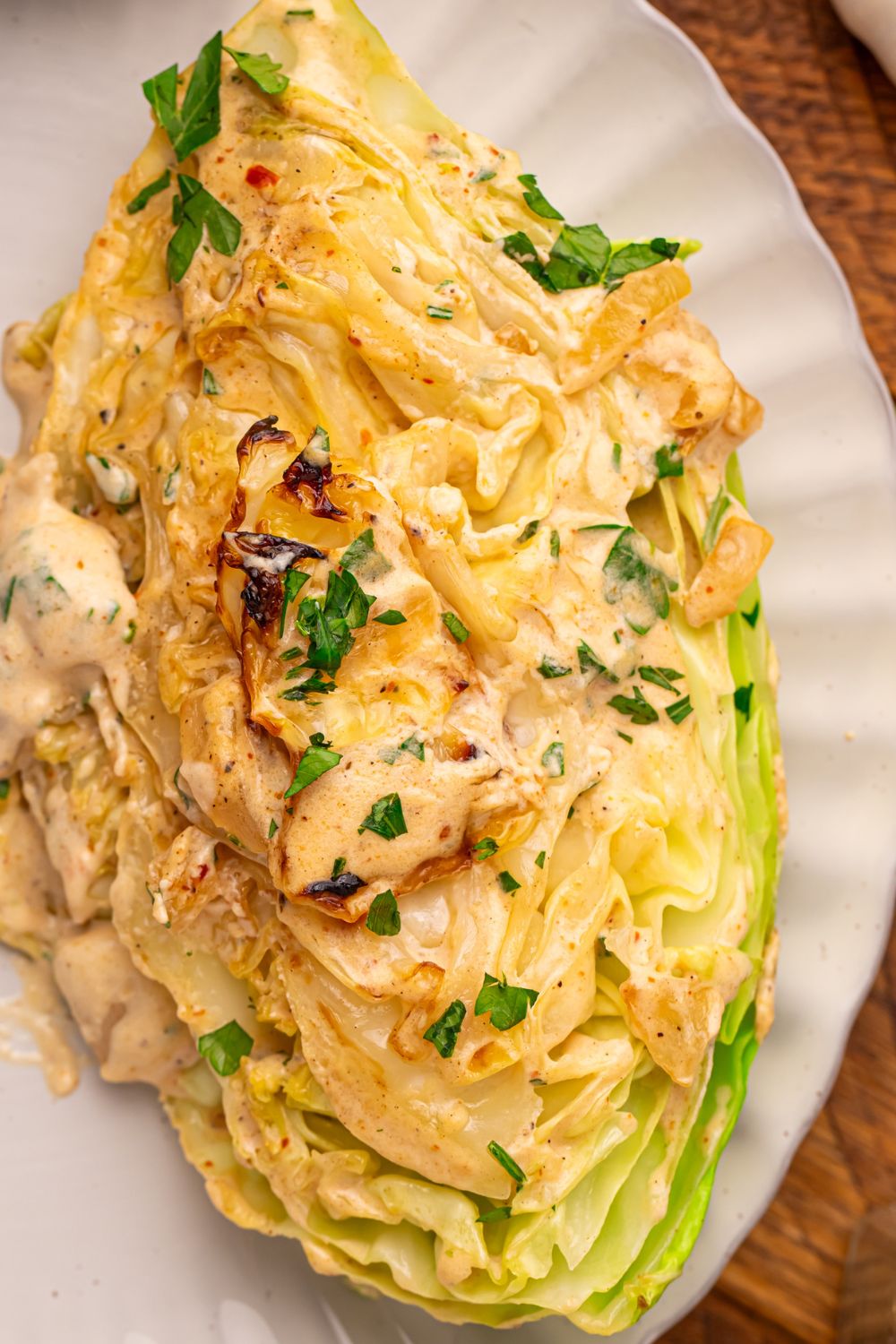 Creamy Garlic Parmesan Cabbage wedge on a plate topped with some parsley 